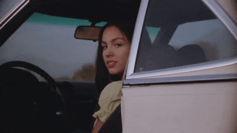 Olivia Rodrigo no clipe de Drivers License, olhando pela porta aberta do carro