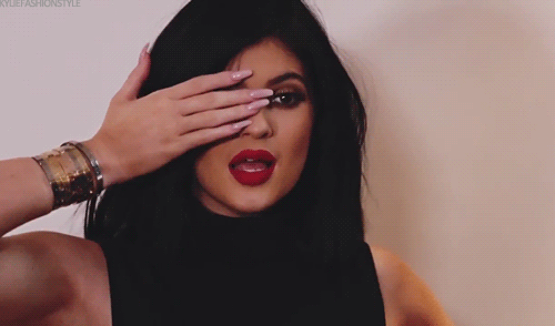 Kylie Jenner cobrindo um dos olhos com uma das mãos e usando uma regata preta de gola alta