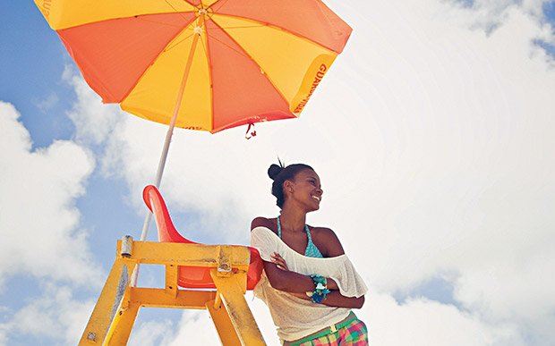 garota na praia sob um guarda sol