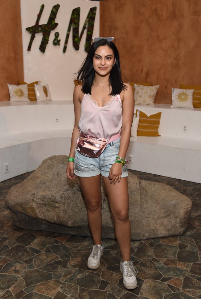 Camila-mendes-look-do-dia Camila Mendes posando em evento da H&M usando visual da marca, blusinha de alça com short jeans e pochete.