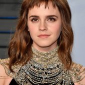 Emma Watson com expressão séria usando múltiplos colares.