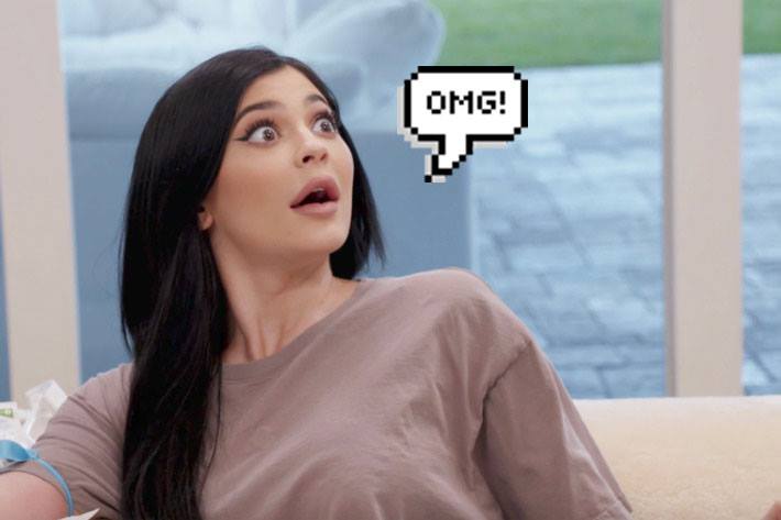 Kylie Jenner usando moletom marrom e fazendo expressão facial de surpresa com os olhos arregalados e boca aberta. Ao lado dela, há um balãozinho de fala escrito "OMG!"