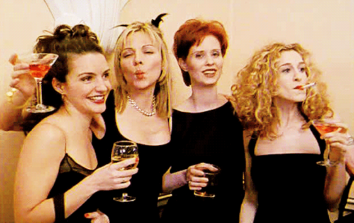Gif das quatro protagonistas de Sex and The City; todas vestem preto e estão sorrindo e mandando beijos para câmera