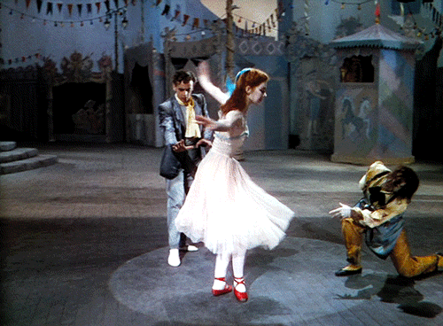 Bailarina dançando na peça O Mágico de Oz; ela está dando piruetas com seu sapatinho vermelho