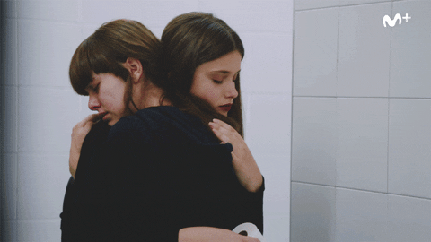 Uma garota consolando outra, por meio de um abraço.
