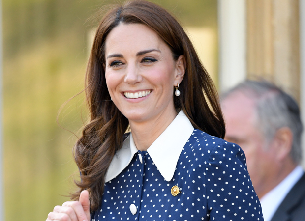 kate-middleton Kate Middleton sorrindo; ela usa uma camisa azul com bolinhas brancas com gola branca