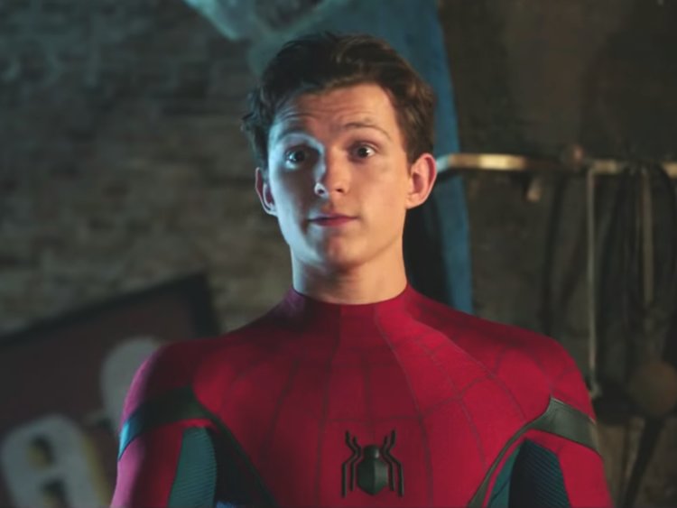Foto do ator Tom Holland como Homem-Aranha. Nela, ele aparece com o traje vermelho e azul com detalhes de aranha do personagem, mas sem a máscara.