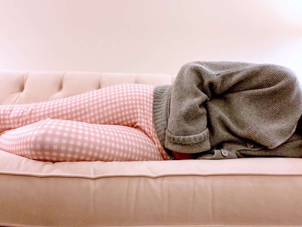 Garota com cólica menstrual deitada no sofá em posição fetal