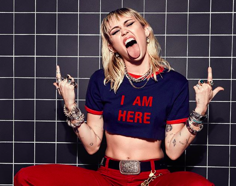 Miley Cyrus mostrando a língua e apontando para cima