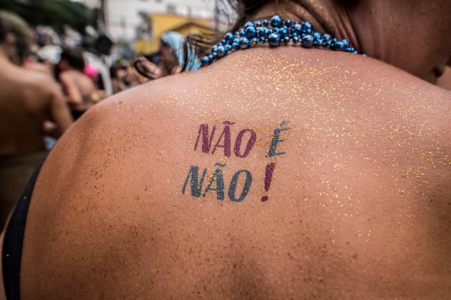 Costas de uma mulher com glitter e uma tatuagem temporária escrita 