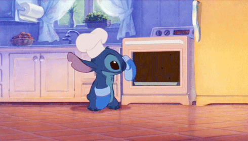 gir do personagem Stitch, com chapéu e luvas de chef de cozinha, retirando um bolo de chocolate do forno.