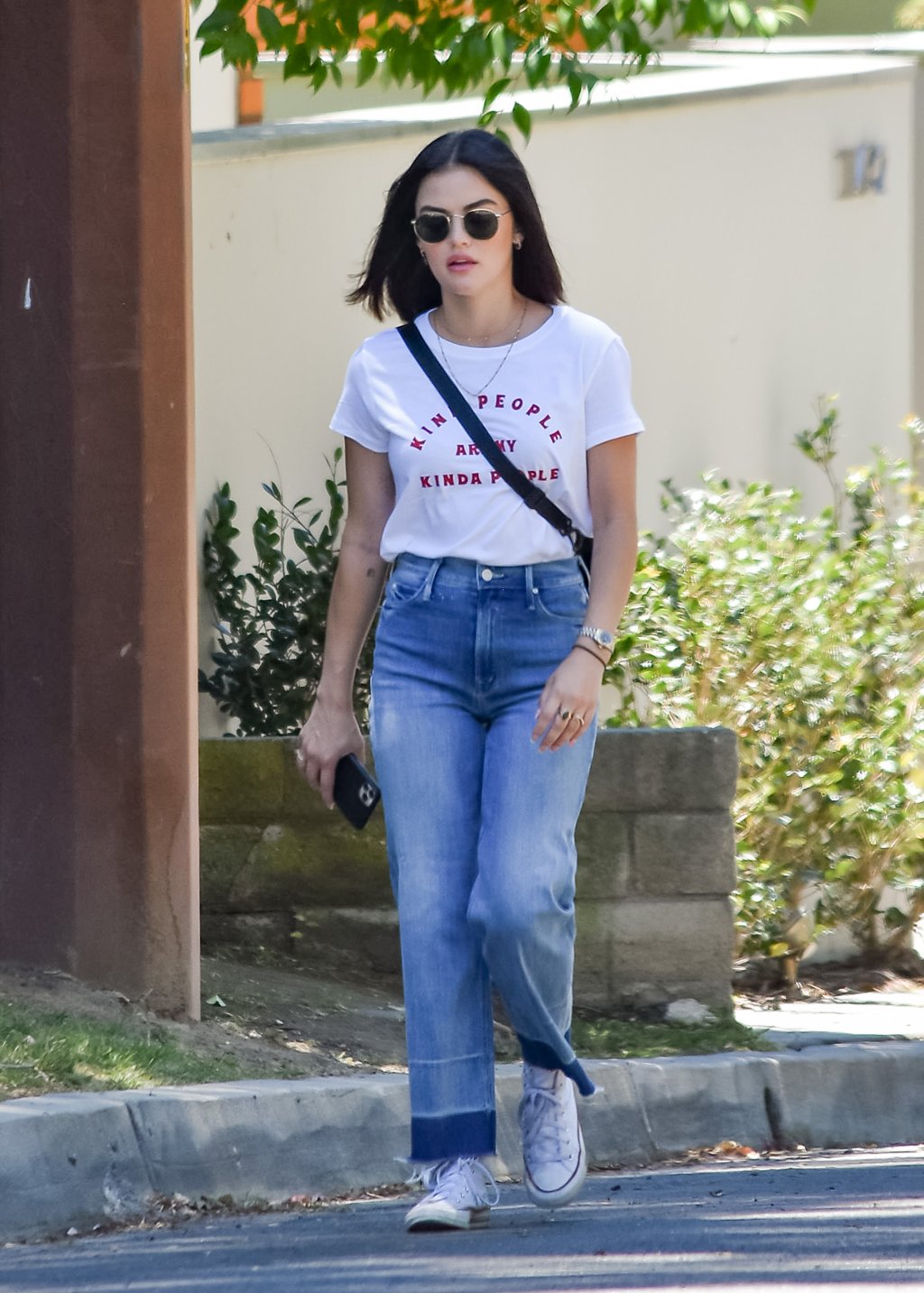 Lucy Hale usando look básico com camiseta, calça jeans e tênis