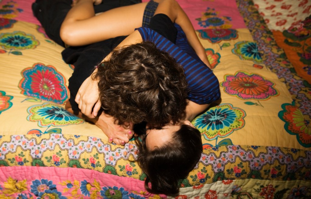 Casal de adolescentes beijando na cama