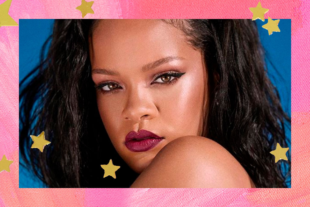 Foto do rosto da Rihanna com olhar sexy para a câmera e batom cor de vinho. A montagem possui fundo rosa e algumas estrelinhas douradas.