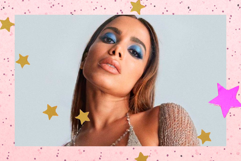 Montagem com foto do rosto da cantora Anitta. Ela está usando uma maquiagem dourada, com expressão séria, olhando para baixo.