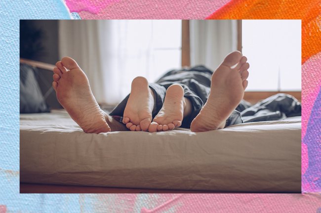 Imagemd e um casal deitado na cama. Eles estão embaixo do lençol e só aparecem os pés