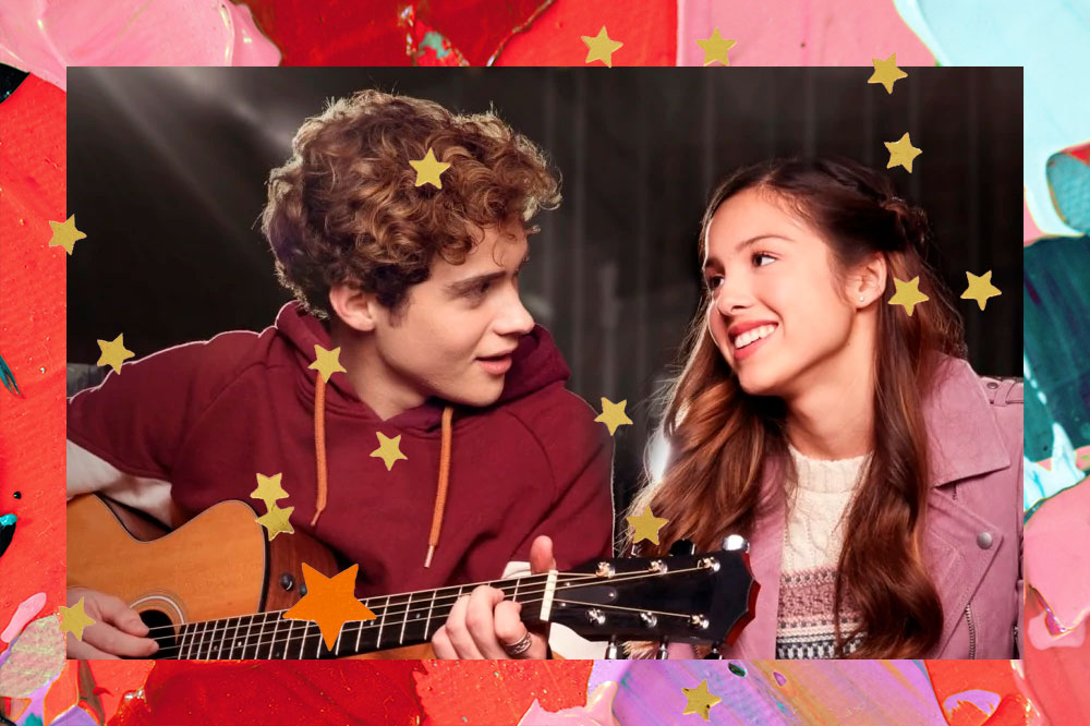 Joshua Basset cantando, tocando violão e olhando para Olivia Rodrigo, que o olha de volta com um sorriso, na série High School Musical: A Série: O Musical