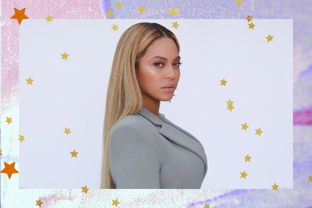 Montagem com foto da Beyoncé em fundo lilás e rosa com estrelinhas douradas e laranjas. Ela está de lado, usando um blazer cinza e olhando para câmera com expressão facial séria.