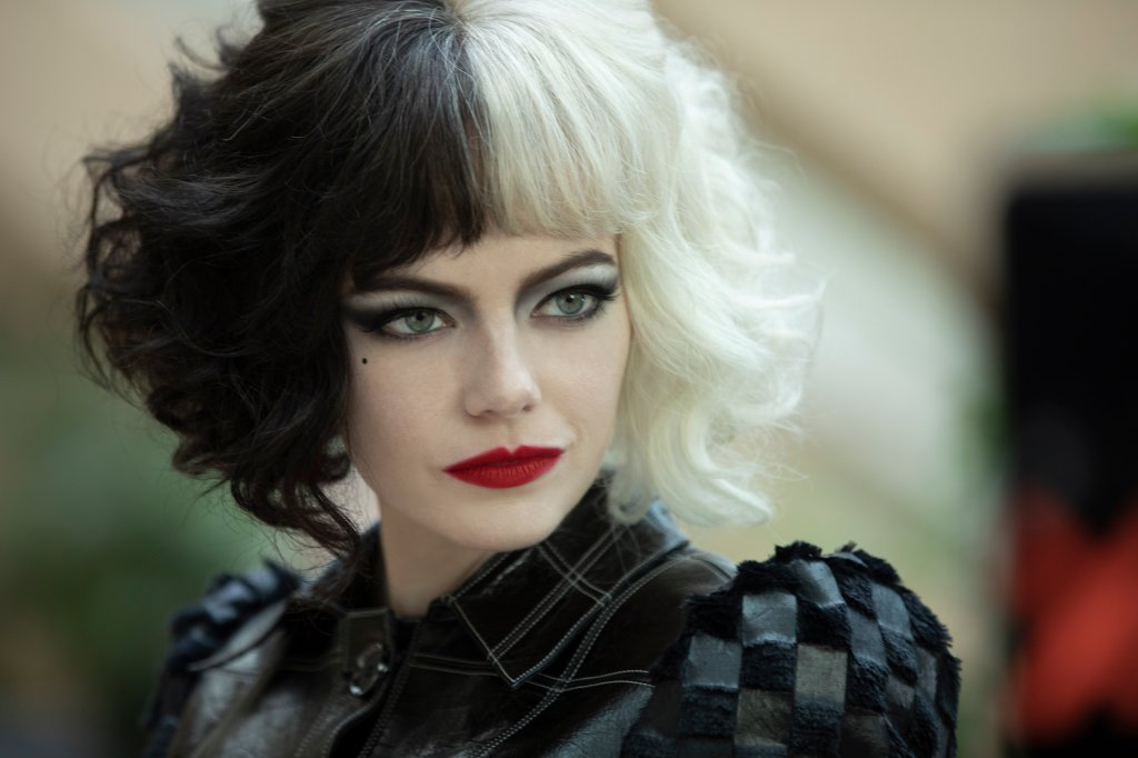 Emma Stone caracterizada como Cruella, com metade do cabelo preto, outra metade loiro platinado e batom vermelho