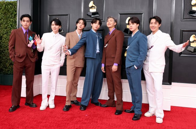 BTS na 64ª edição do GRAMMY Awards; os sete integrantes estão posando no tapete vermelho da premiação em uma fileira na horizontal