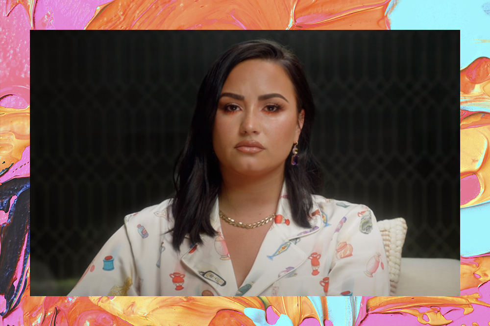 Demi Lovato usando camisa branca com detalhes e expressão séria em imagem de seu documentário