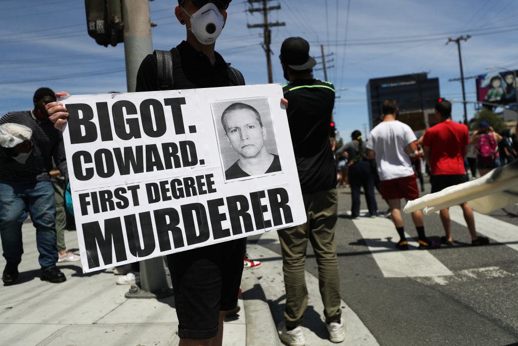 Protesto contra a morte de George Floyd; homem segura cartaz com os dizeres "Grande covarde, assassino", sobre o policial Derek Chauvin