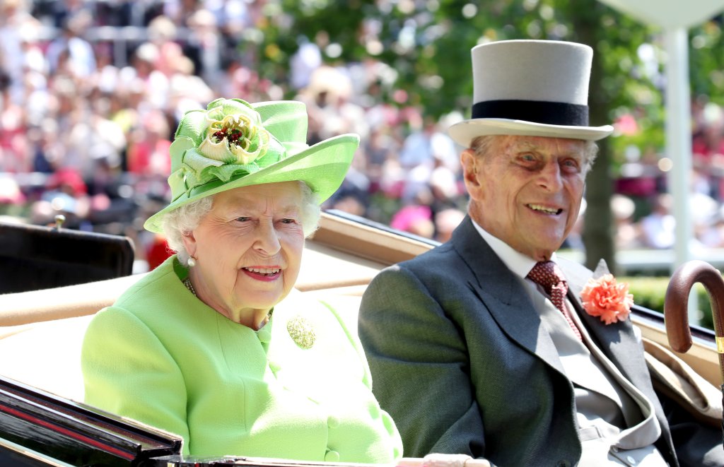 Rainha Elizabeth II em conjunto verde limão e príncipe Philip com chapéu e terno, os dois sorriem para foto