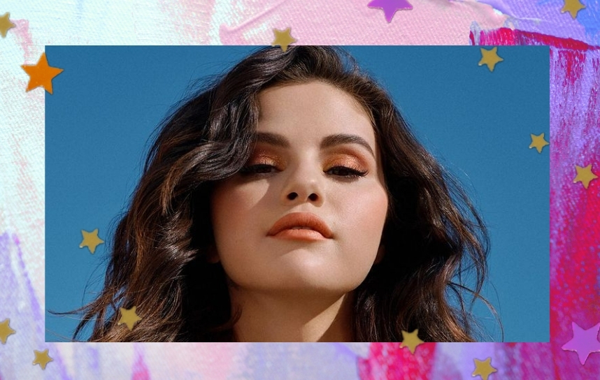 Foto com fundo azul, com close no rosto da cantora Selena Gomez, que aparece com expressão levemente séria, e os olhos quase fechados, exibindo uma maquiagem marrom esfumada e o seu cabelo cacheado.