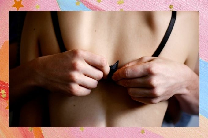 Na imagem, aparece as costas de uma mulher que usa um sutiã preto e duas mãos abrindo o fecho.