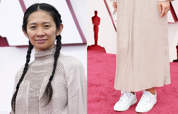 A diretora Chloé Zhao veste um vestido de manga longa nude e um tênis branco no tapete vermelho do Oscar