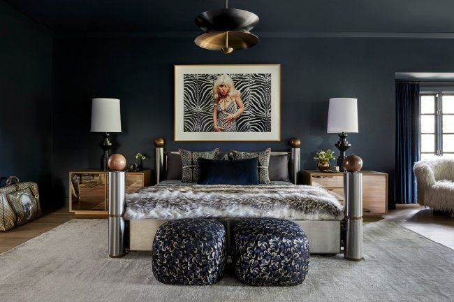 Quarto de Miley Cyrus. Na imagem, aparece uma cama de aço inoxidável, um quadro com a imagem de Debbie Harry e uma luminária em cada canto da cama. As cores que predominam a imagem são cinza, preto e azul marinho.