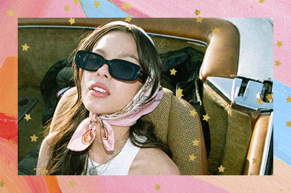 Olivia Rodrigo com óculos de sol e lenço dentro de um carro