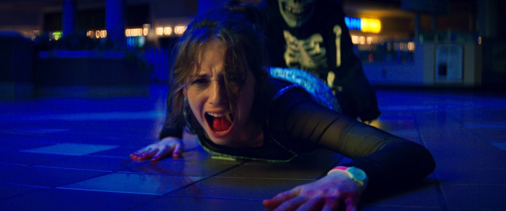 Maya Hawke como Heather em imagem promocional de Rua do Medo, ela está gritando enquanto alguém a arrasta pelo chão