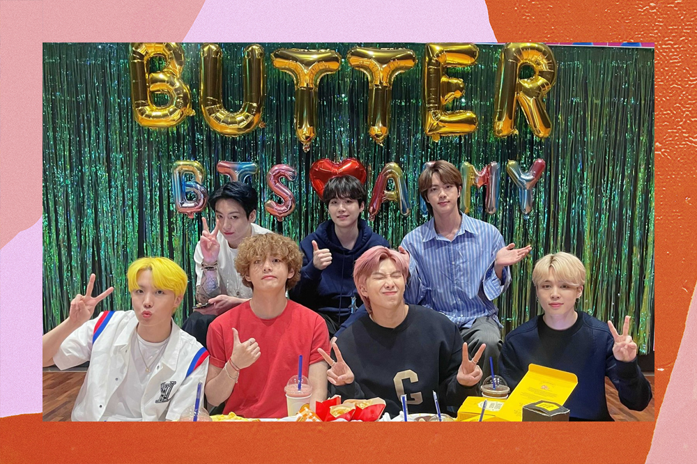 Septeto do BTS reunido diante de uma mesa com comidas, atrás há balões de festa escrito Butter
