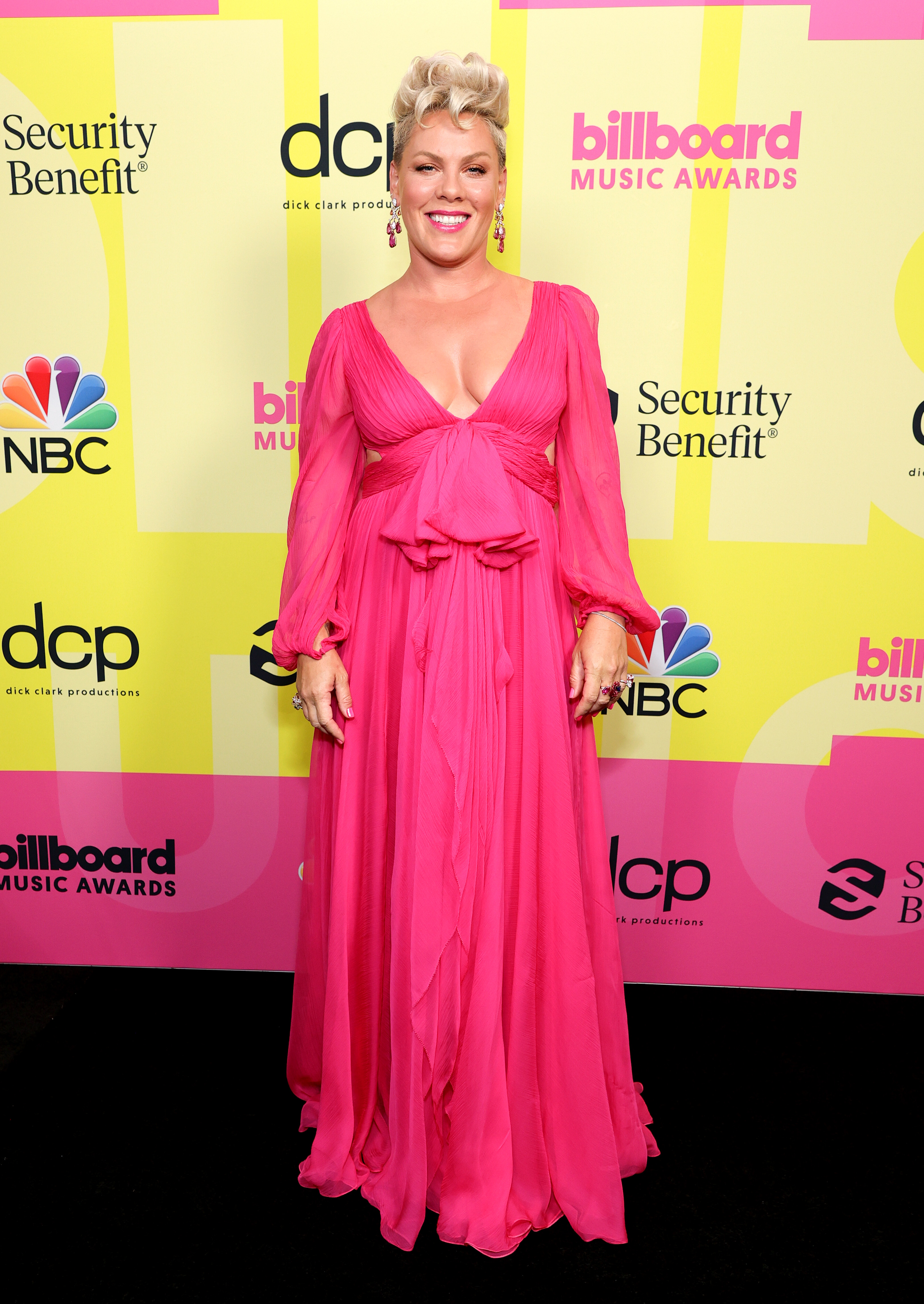 pink-billboard-music-awards Pink usando vestido longo rosa esvoaçante no Billboard Music Awards 2021. Ela está sorrindo e olhando para a câmera.