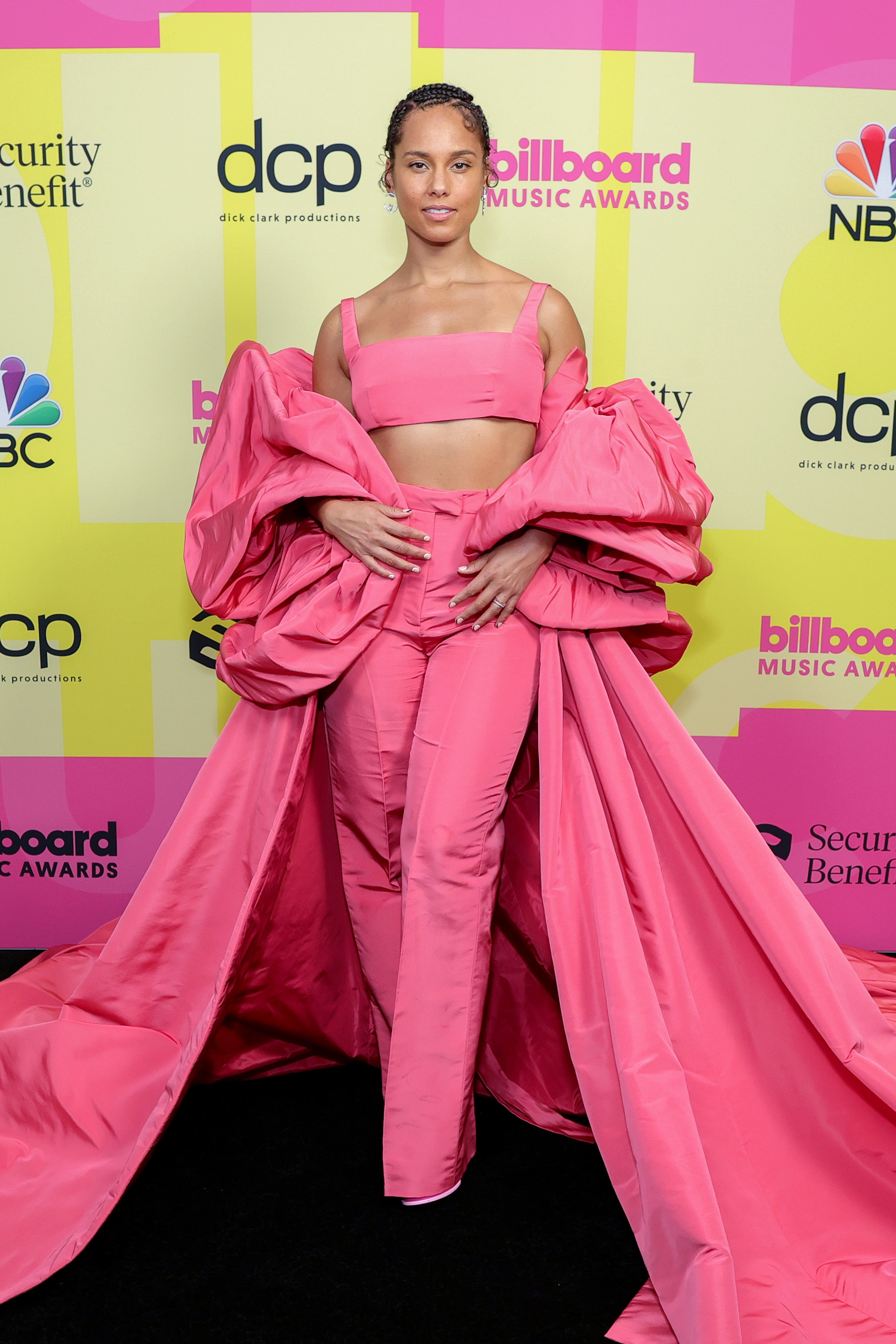 alicia-keys-billboard-music-awards Alicia Keys no Billboard Music Awards 2021. Ela está usando um look todo rosa com top cropped, calça de alfaiataria e uma espécie de capa volumosa por cima.