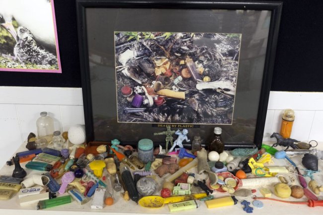 Uma mesa cheinha de lixo plástico que foi retirado do estômago de um albatroz. Tem peças de todos os tipos, tamanhos e cores. Tem até bexiga.