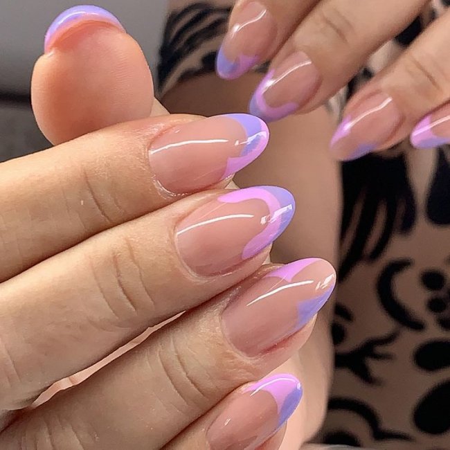 Foto mostrando uma mão com os dedos dobrados para evidenciar as unhas pintadas em francesinha colorida lilás