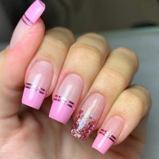 Foto mostrando uma mão com os dedos dobrados para evidenciar as unhas pintadas em francesinha colorida com glitter e rosa