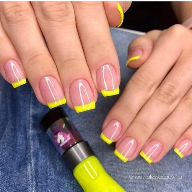 Foto mostrando uma mão com os dedos dobrados para evidenciar as unhas pintadas em francesinha colorida amarela