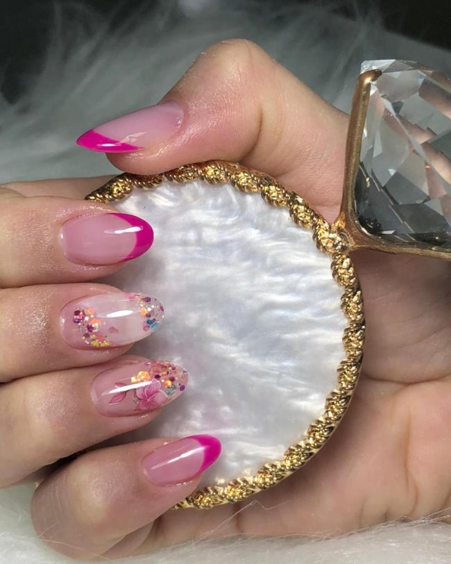 Foto mostrando uma mão com os dedos dobrados para evidenciar as unhas pintadas em francesinha colorida rosa e com detalhes em glitter
