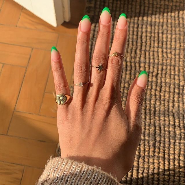 Foto mostrando uma mão com os dedos dobrados para evidenciar as unhas pintadas em francesinha colorida na cor verde.