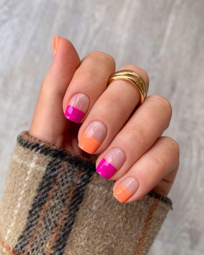 Foto mostrando uma mão com os dedos dobrados para evidenciar as unhas pintadas em francesinha colorida nas cores laranja e rosa
