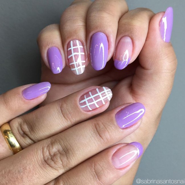Foto mostrando uma mão com os dedos dobrados para evidenciar as unhas pintadas em francesinha colorida lilás com detalhes quadriculado branco