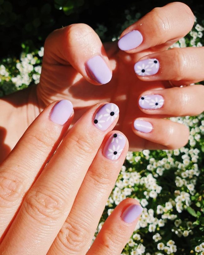 Nail art simples com florzinha em fundo lilás
