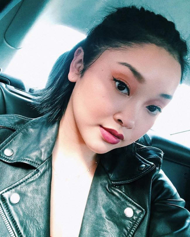 lana condor make dia a dia Selfie da atriz Lana Condor. Ela usa uma jaqueta de couro preta, cabelo meio preso e maquigem com sombra marrom, delineado e batom nude. Ela olha para a câmera e não sorri.