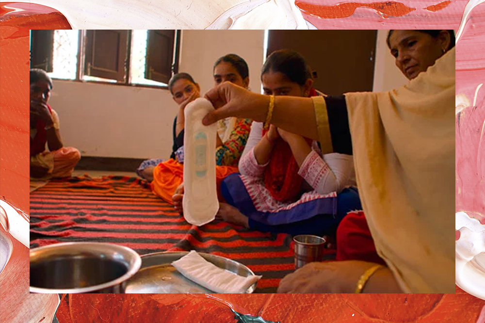 Adolescentes indianas olham para um absorvente descartável que está sendo mostrado por uma mulher mais velha