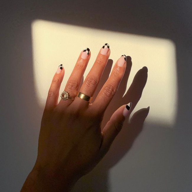 nail_art_xadrez Foto de uma mão com anéis dourados no dedo anelar e médio. Com nail art xadrez preto e branco como francesinha.