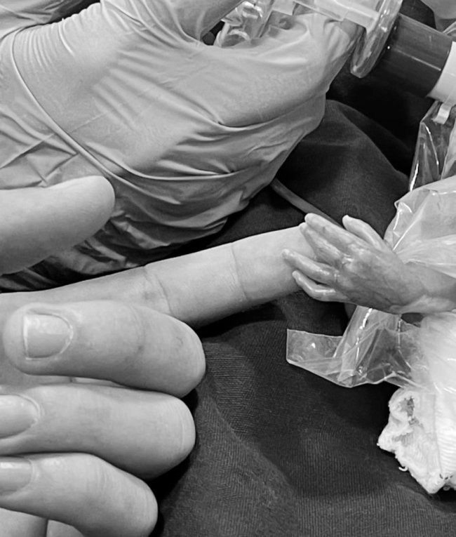 Foto em preto e branco de Whindersson Nunes; só aparece o dedo do humorista, que encosta na mão do filho prematuro