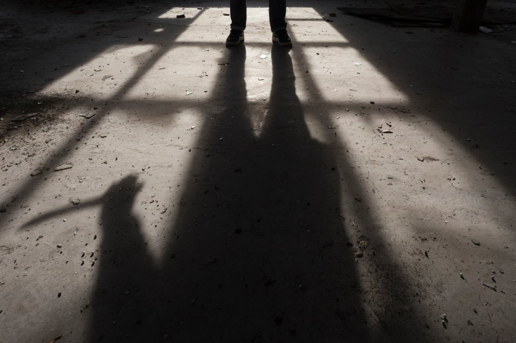 Foto da sombra de um homem com grande faca na mão, dentro de uma casa, assustador